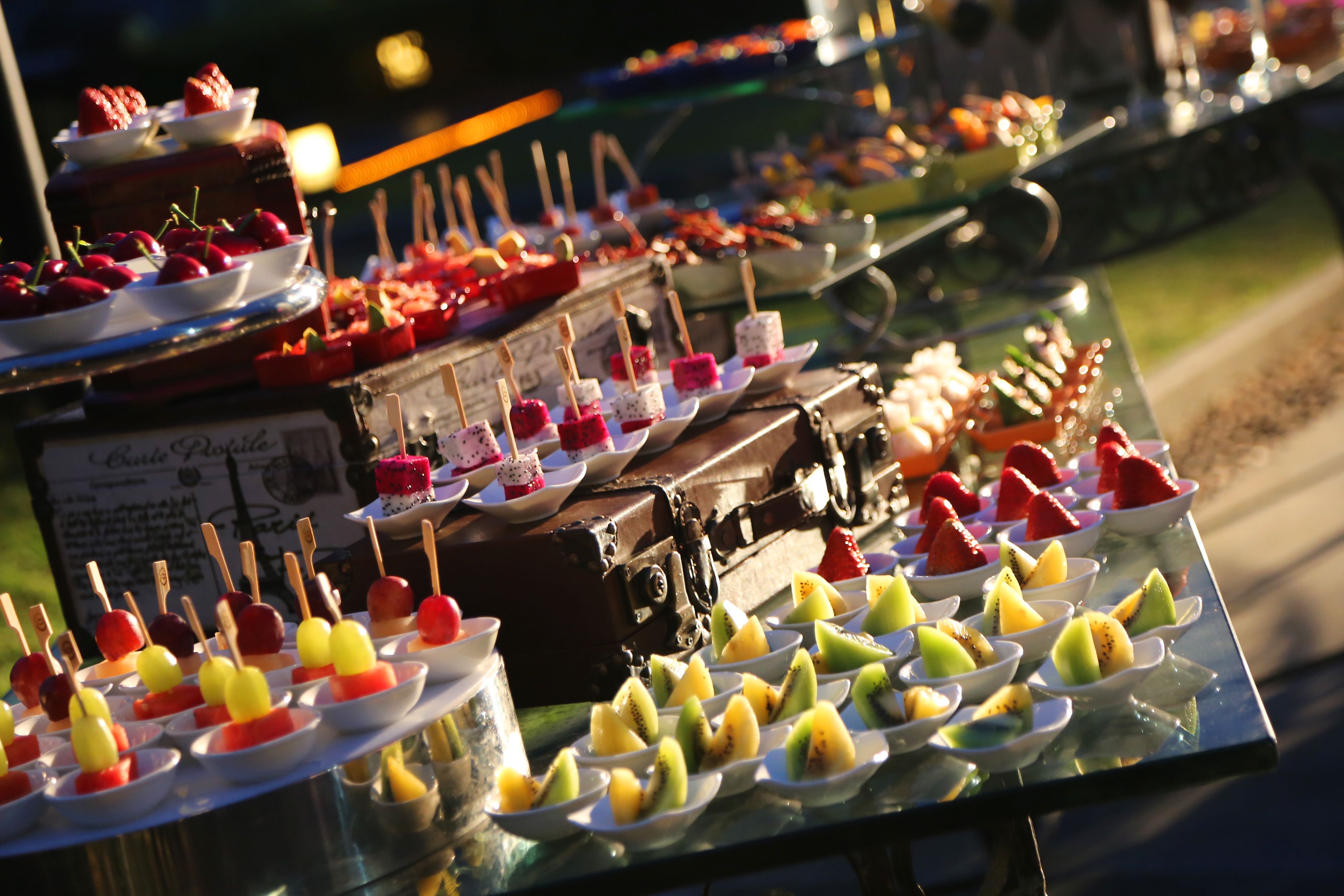 A table with various fruit skewers and desserts.