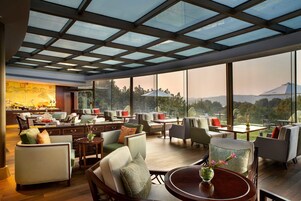 Un amplio salón con asientos cómodos, techo de cristal y ventanas grandes que ofrecen vistas al exterior.