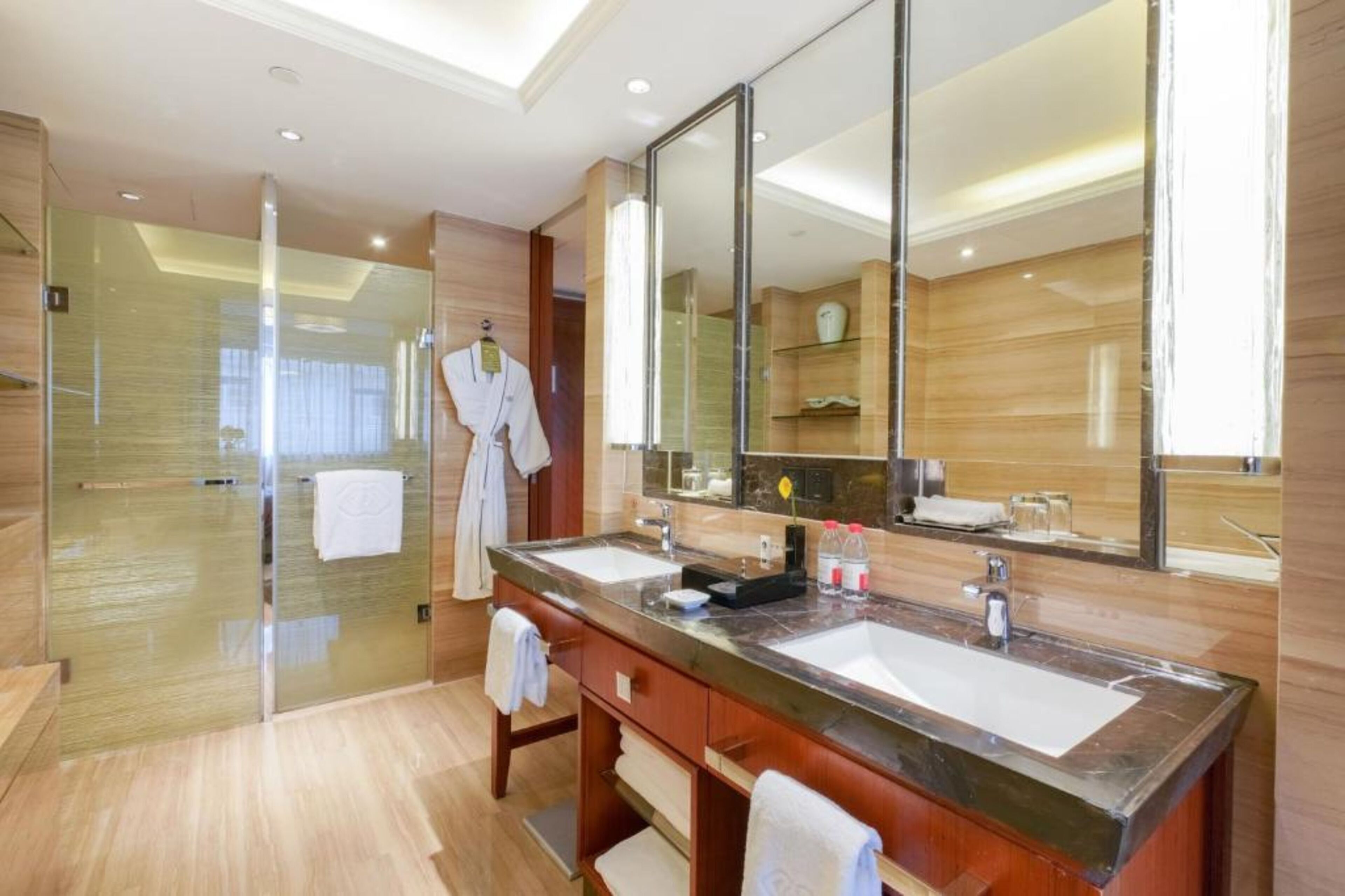 A modern bathroom with two sinks, a large mirror, and a glass shower enclosure.