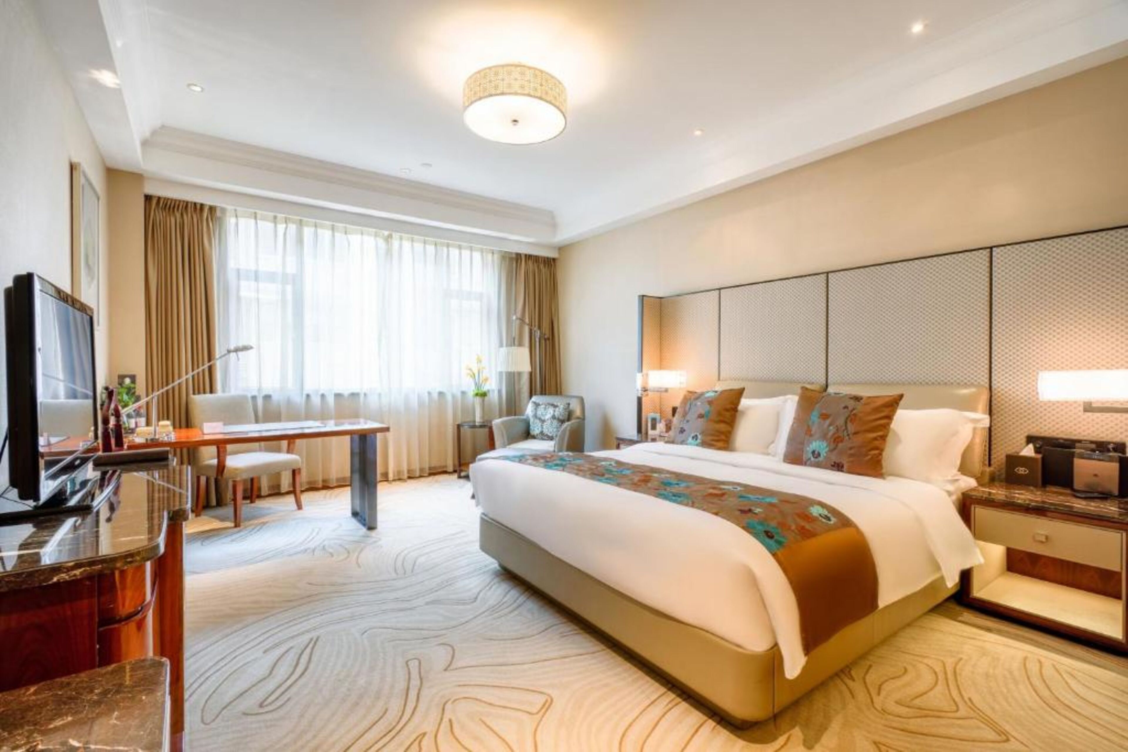 Habitación de hotel con una cama grande, un escritorio, un televisor y vistas al exterior a través de la ventana.