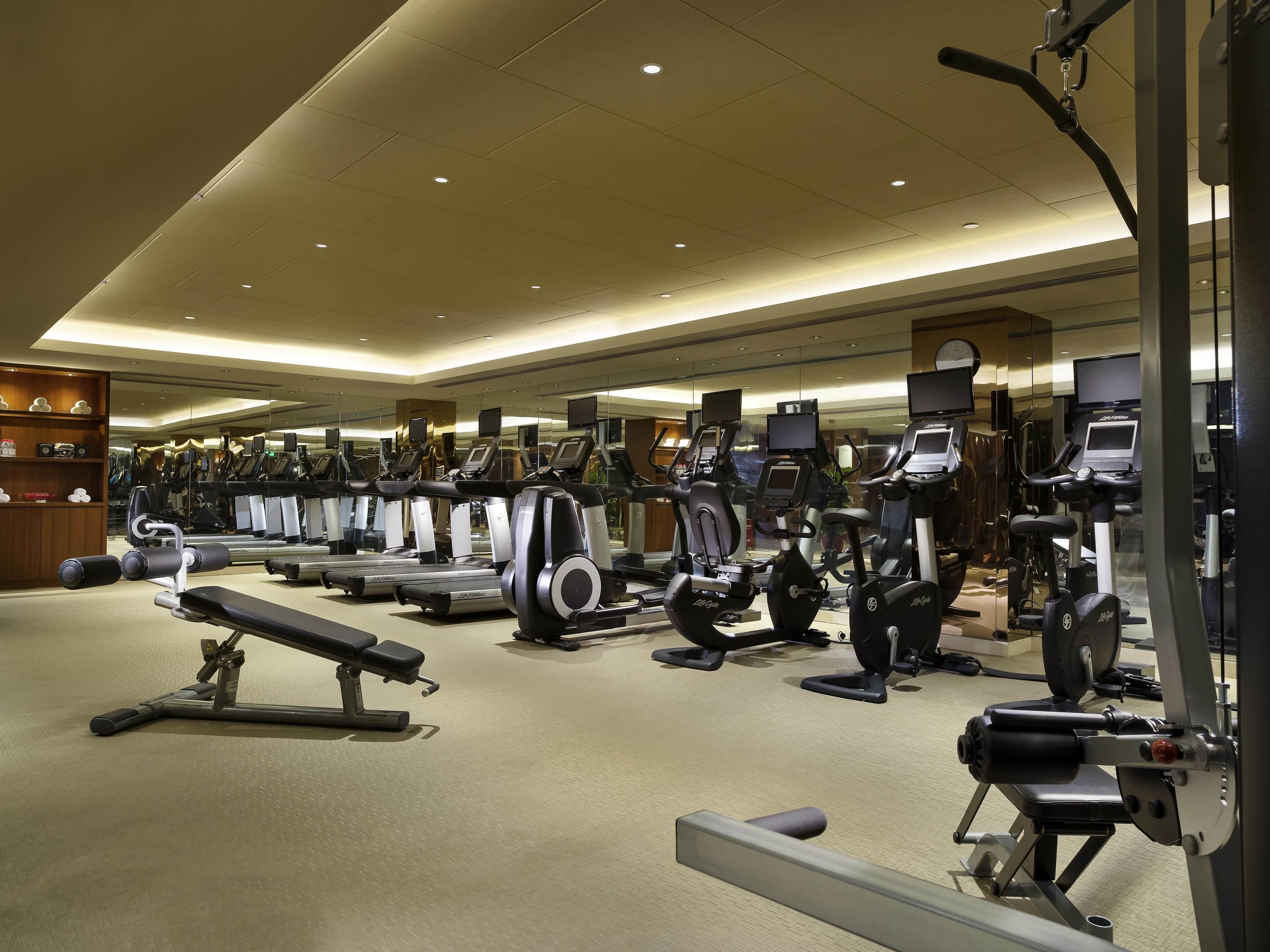 A gym with multiple treadmills, ellipticals, and weight machines.