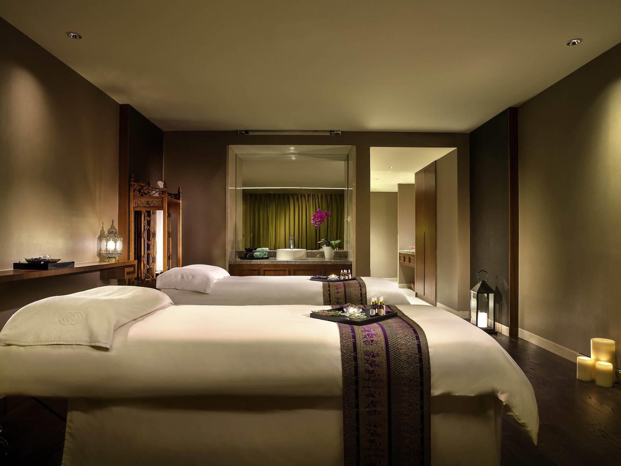 A hotel room with two beds, a large mirror, a vanity with a sink, and a small table with toiletries.