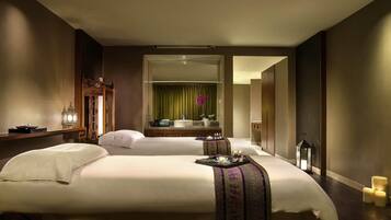 A hotel room with two beds, a large mirror, a vanity with a sink, and a small table with toiletries.
