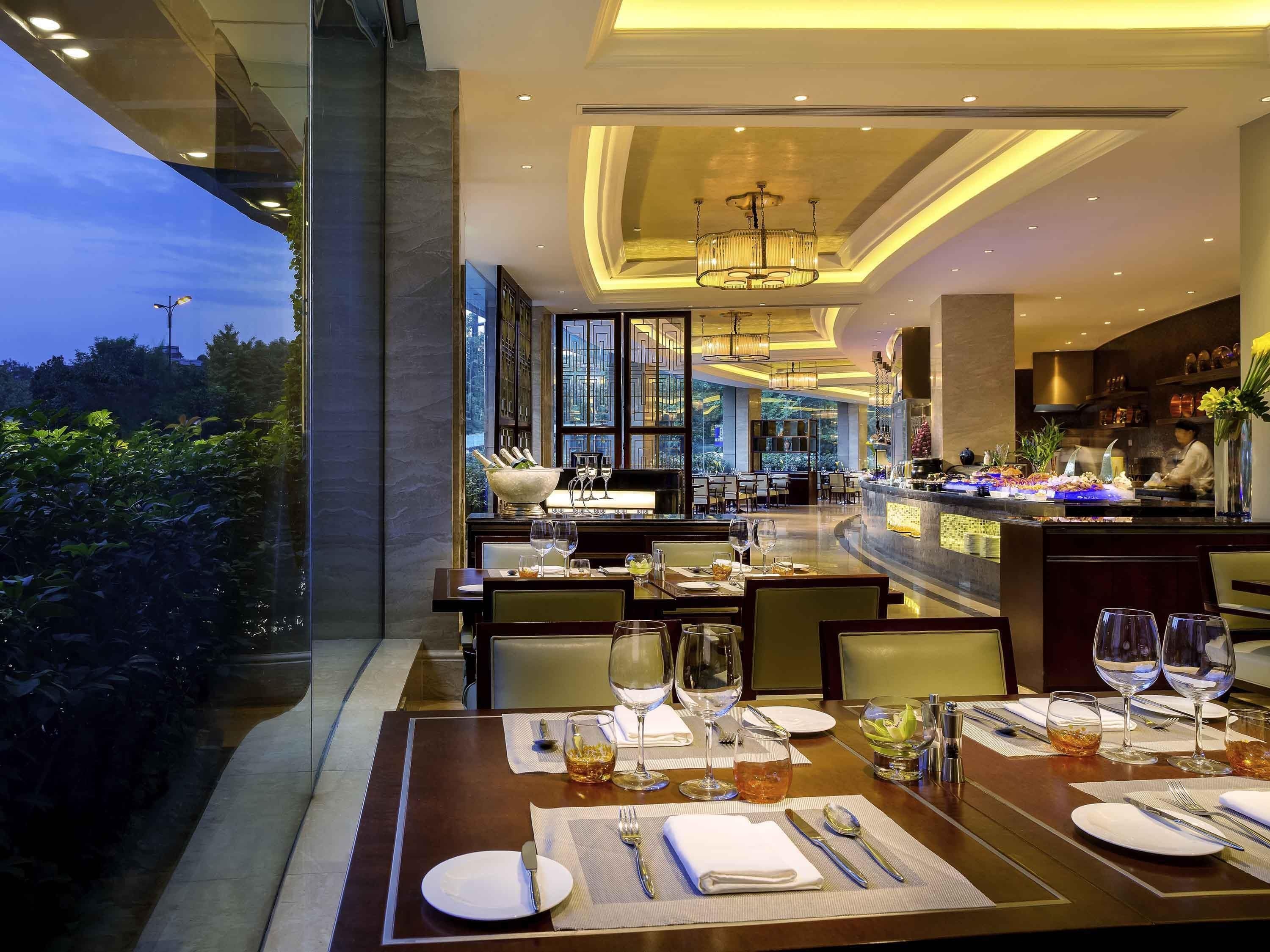 Un restaurante bien iluminado con mesas dispuestas para comer, una zona de bar y vistas al exterior.