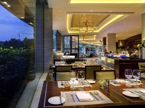 A well-lit restaurant with tables set for dining, a bar area, and a view of the outdoors. - Sofitel Hangzhou Westlake (Hangzhou)