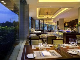 Un restaurante bien iluminado con mesas dispuestas para comer, una zona de bar y vistas al exterior.