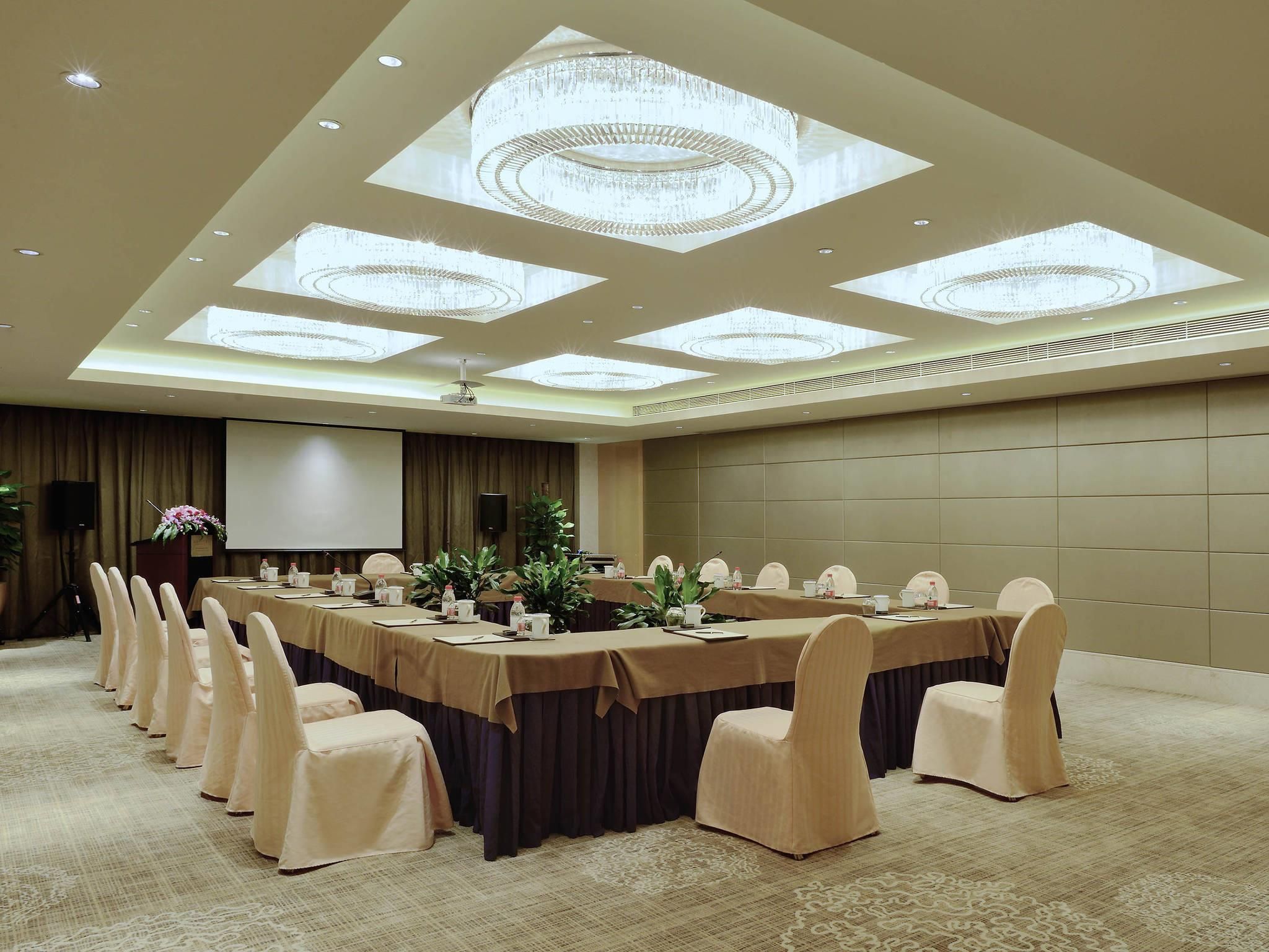 A conference room with a long table, chairs, a podium, and a screen.