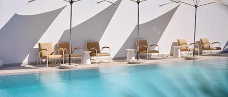 Una piscina al aire libre de temporada, sombrillas