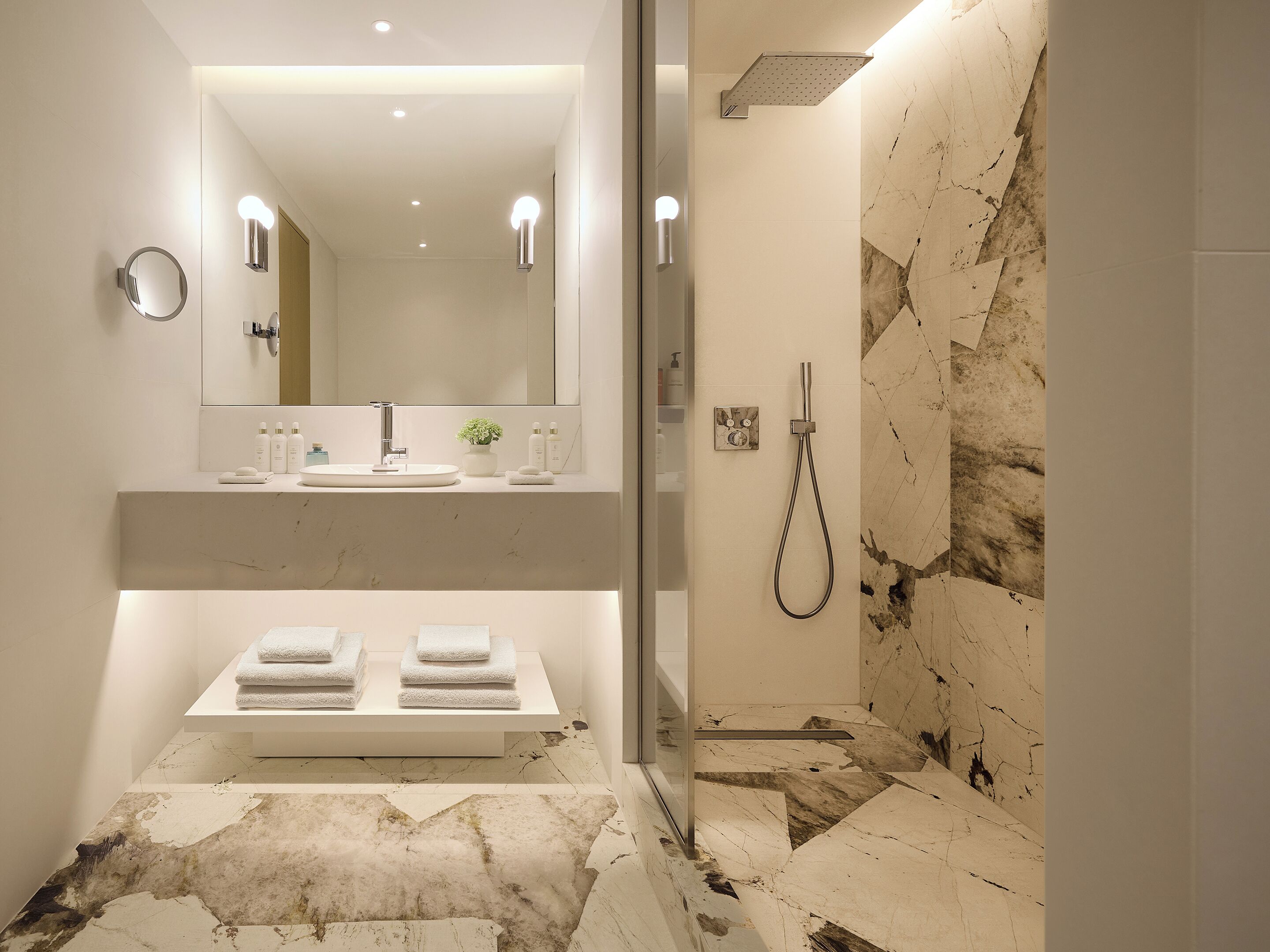 A modern bathroom with a large mirror, a sink, and a shower.