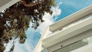 A modern building with a clear sky and a tree in the foreground.