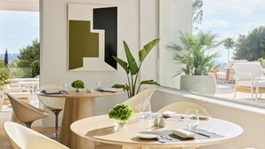 A modern dining area with round tables, white chairs, and a view of the outdoors.