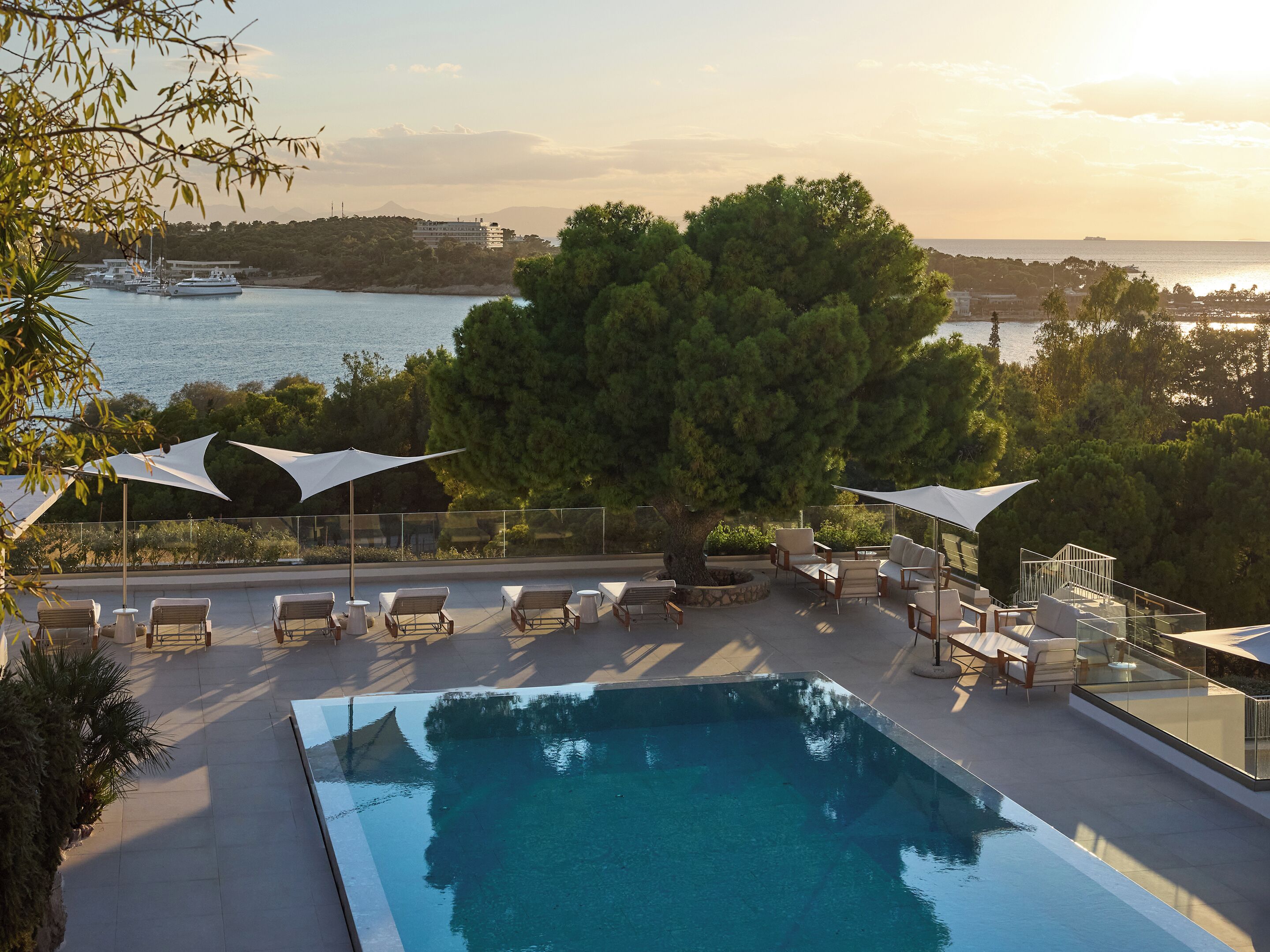 Una piscina al aire libre, sombrillas, sillones reclinables de piscina