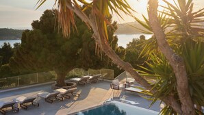 A poolside area with lounge chairs and a view of the sea.