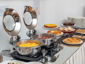 Ein reichhaltiges Buffet mit verschiedenen Speisen, darunter ein Käsesgericht, ein Fleischgericht und mehrere Desserts.