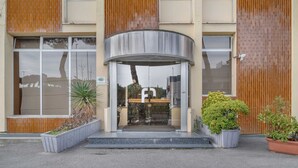 A building with a brick facade, large windows, and a covered entrance. - B&B HOTEL CALENZANO FIRST (Calenzano)