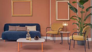 A living room with a blue sofa, a coffee table, two chairs, and a large plant.