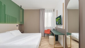 A hotel room with a bed, a desk, a chair, a mirror, and a TV on the wall. - B&B HOTEL CALENZANO FIRST (Calenzano)