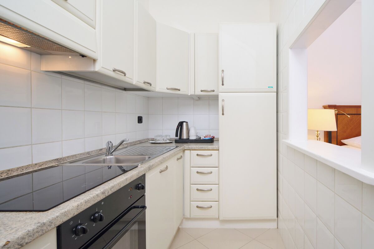 Una cocina moderna con armarios blancos, una estufa negra y un lavamanos de acero inoxidable.
