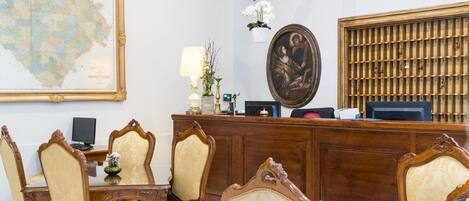 A reception area with a wooden desk, chairs, a map, and a religious painting.