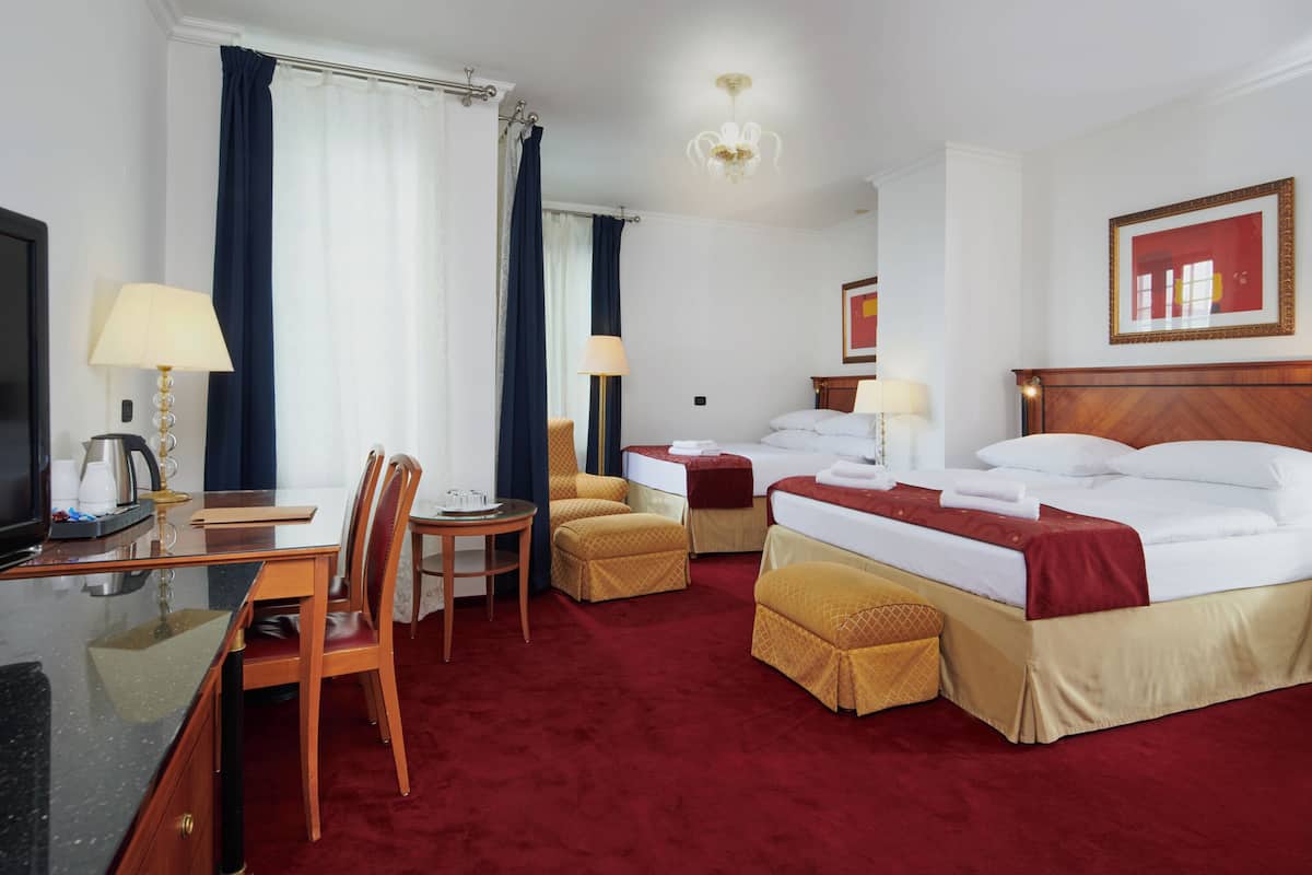 Habitación de hotel con cama, dos mesitas de noche, escritorio con silla, televisor y lámpara.