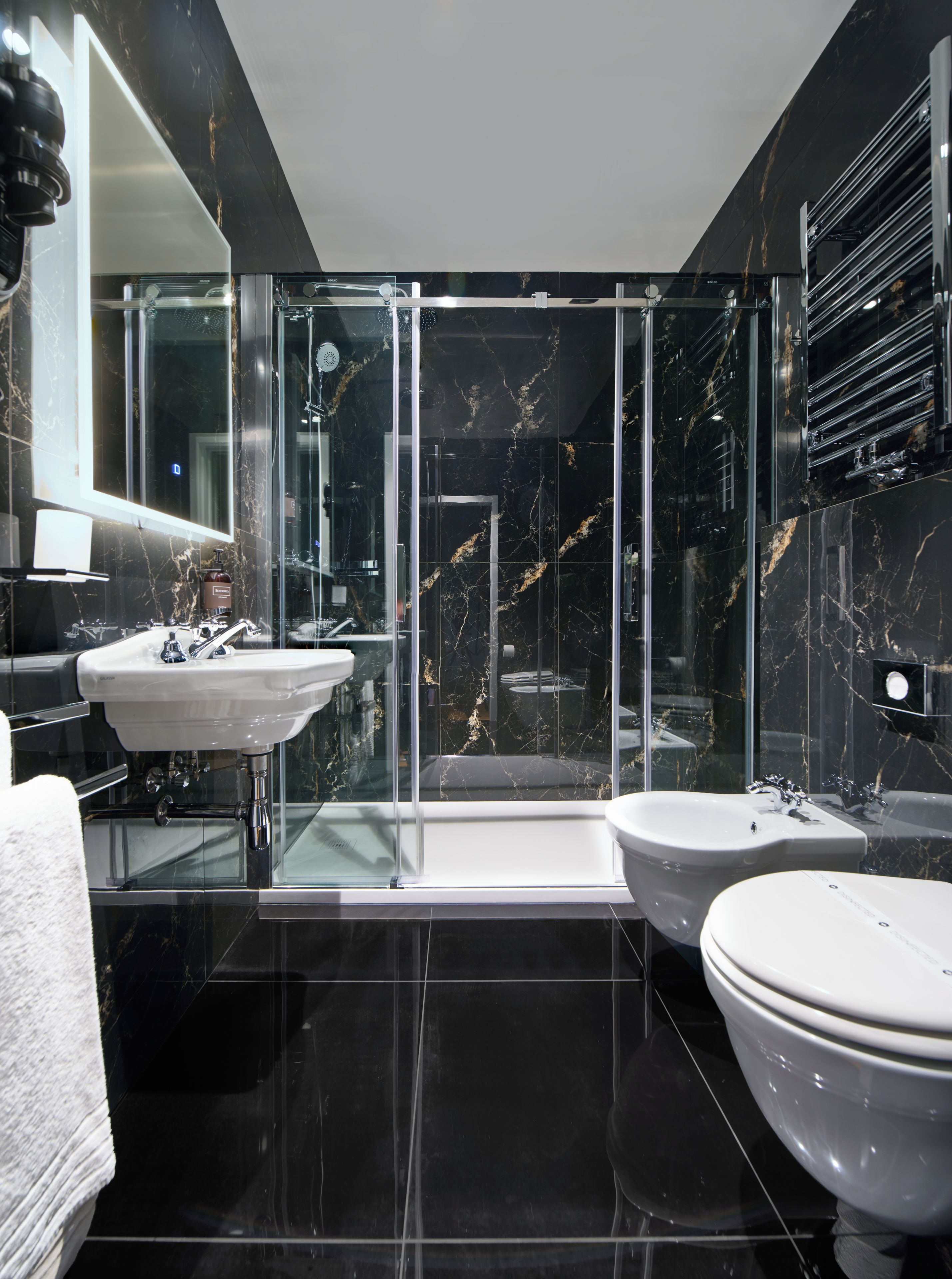 Un baño moderno con ducha envuelta en vidrio, un lavabo blanco y un bidé.