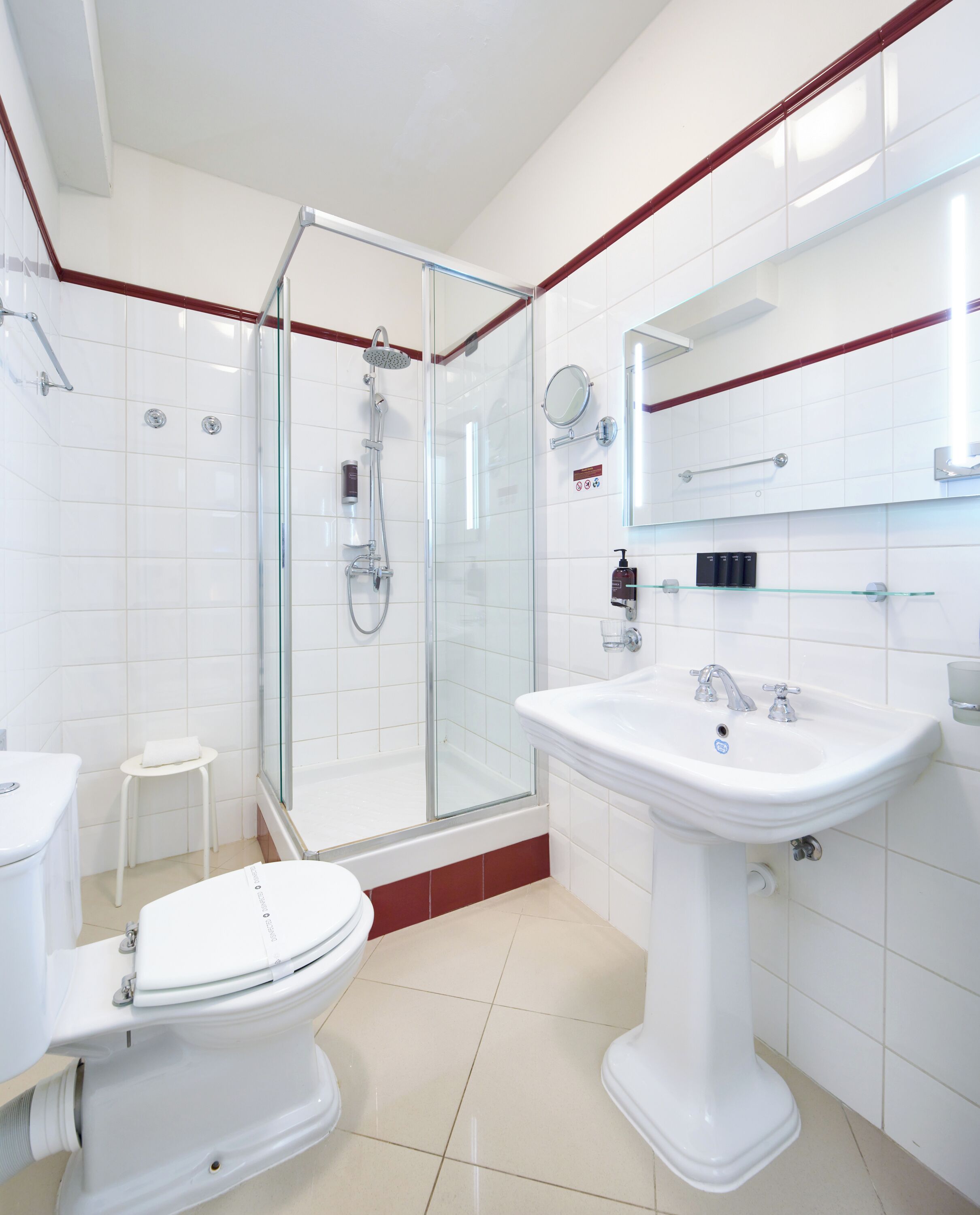 Un baño moderno con ducha acristalada, lavamanos blanco y retrete.