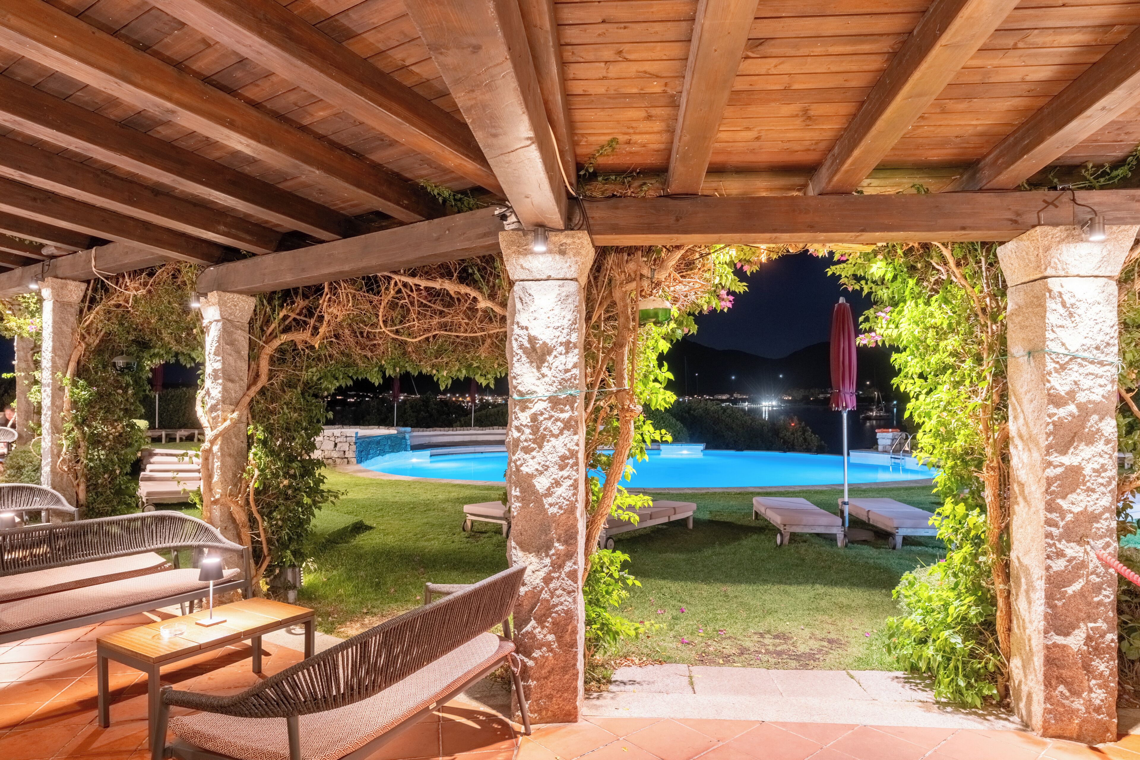 Un espace extérieur abrité comprenant une piscine, des bancs et une structure en forme de pergola.