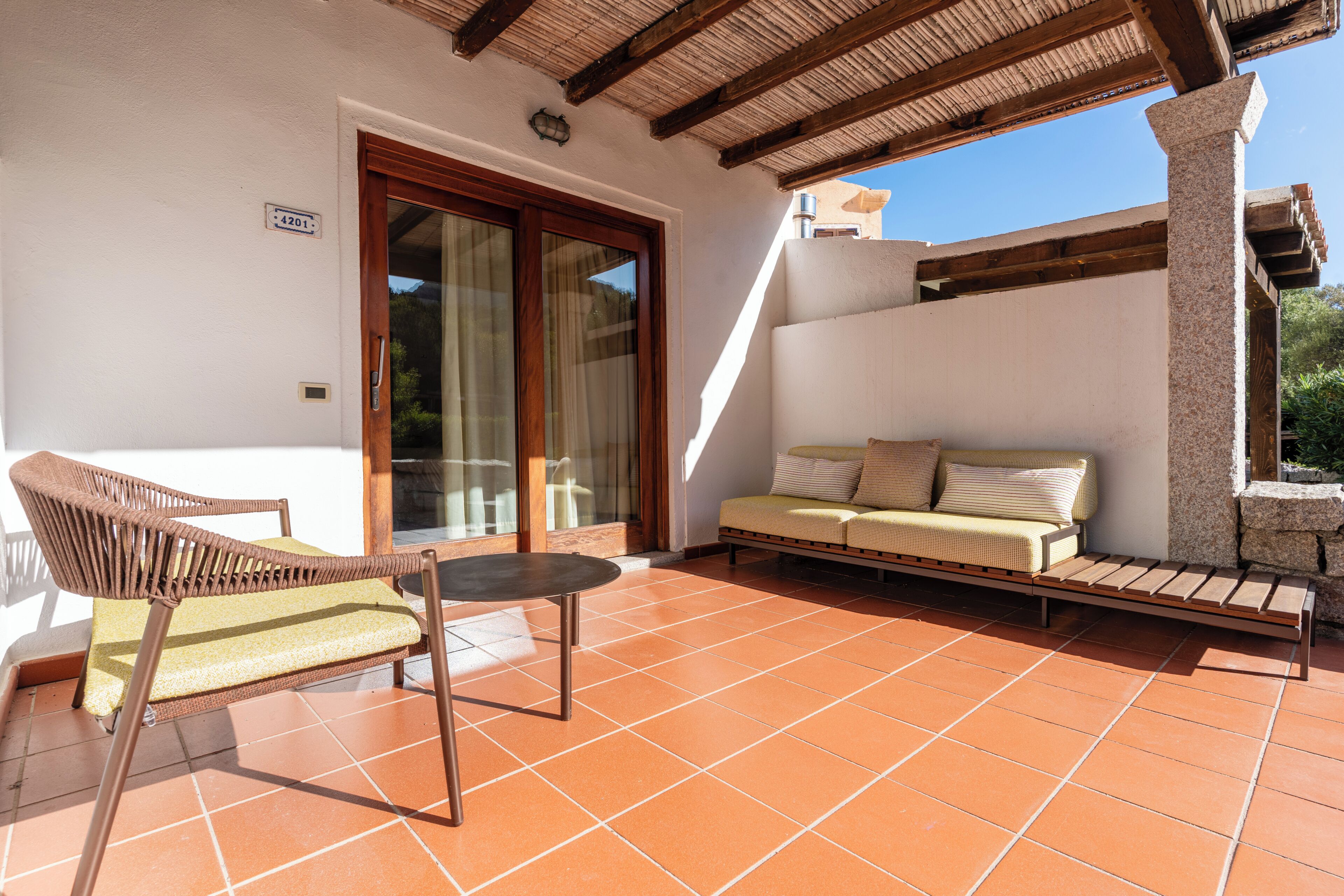 A covered patio with a sofa, a chair, and a small table.