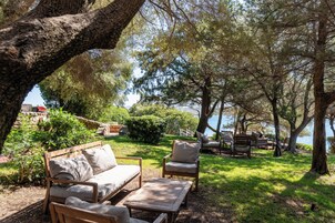 An outdoor seating area with wooden furniture, a stone wall, and a view of the water.