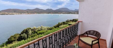 Uma varanda com vista para um lago, uma cadeira e uma mesa.
