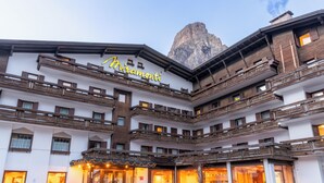A multi-story hotel with balconies, a mountain view, and a sign reading 'Miramonti.'