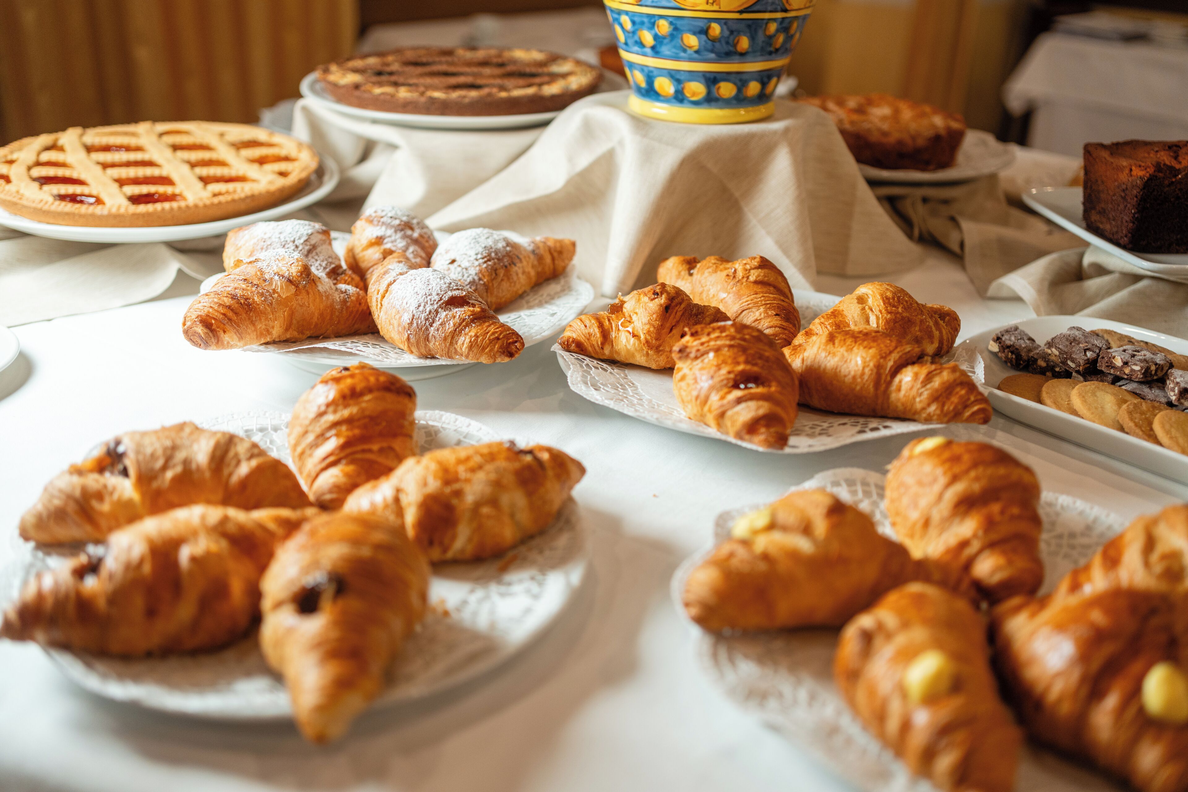 A table with various baked goods, including croissants and pies.