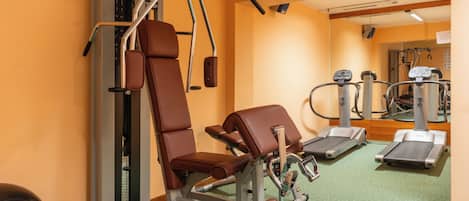 Une salle de sport équipée de matériel d’exercice, d’un tapis de course et d’un banc de musculation.