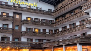 A multi-story hotel with balconies, a prominent sign, and a mountain backdrop.