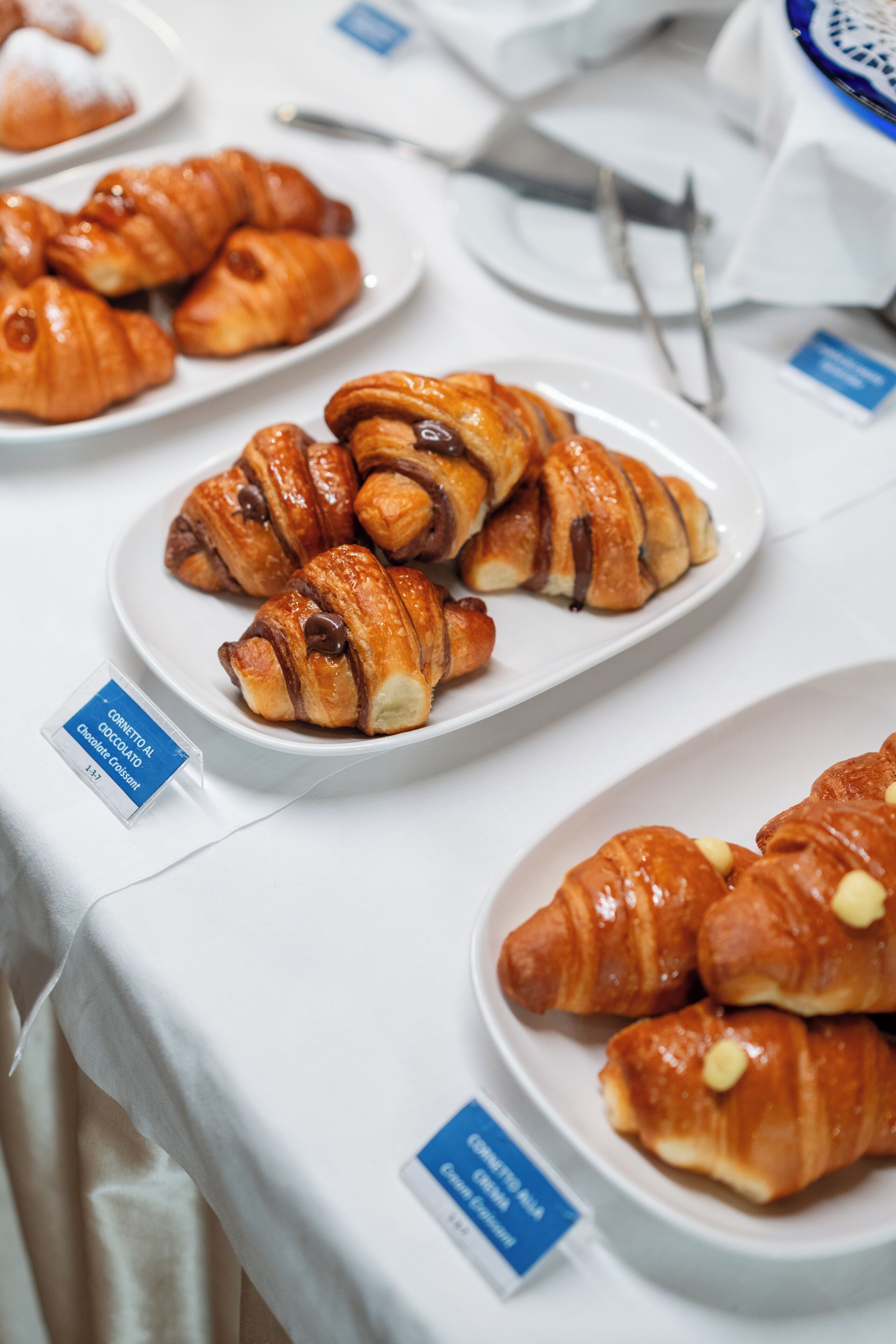 A table with plates of croissants, some with chocolate and others with white chocolate.