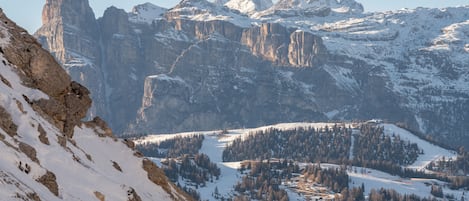 A mountainous landscape with snow-covered peaks and a valley with trees.