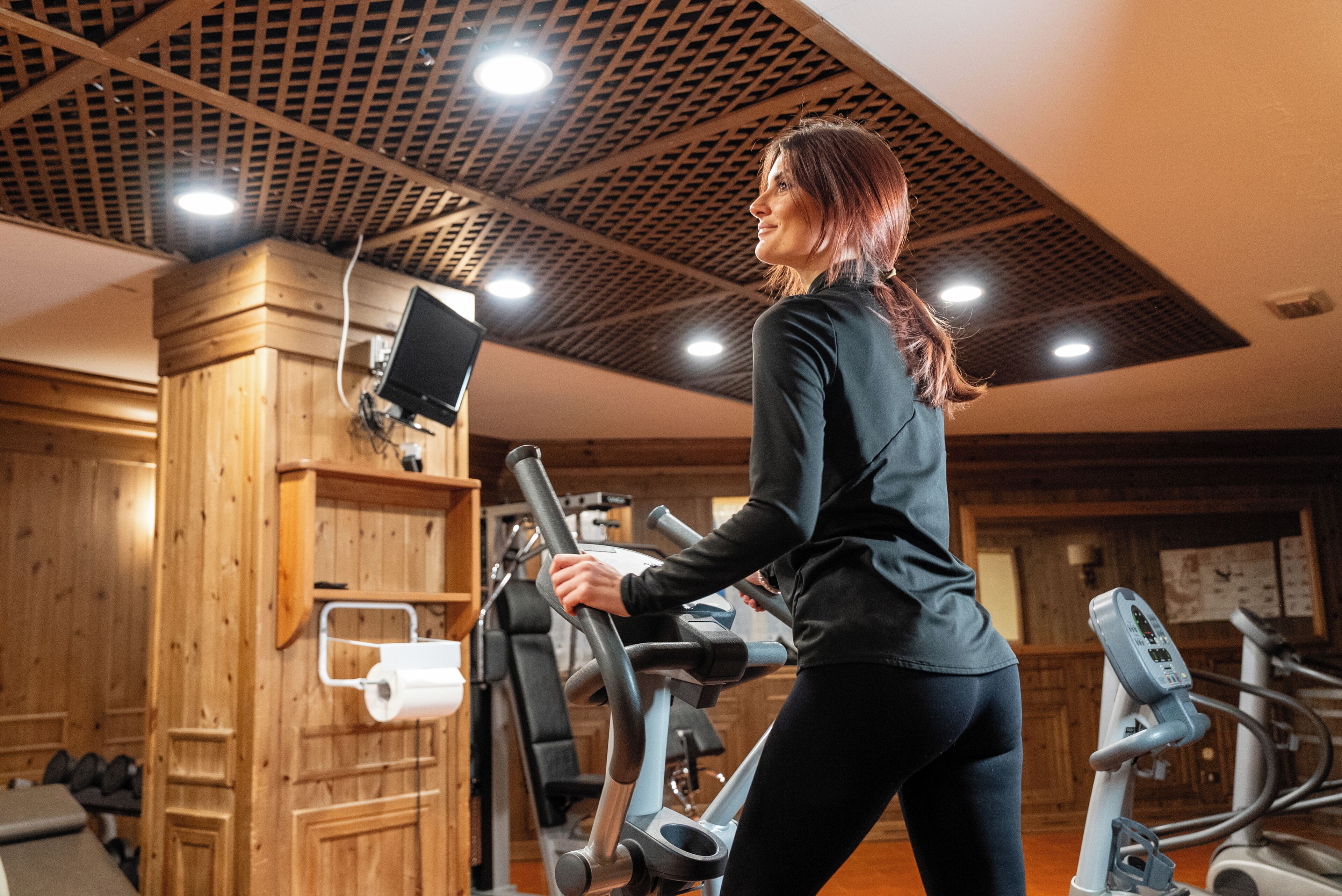 A gym with wooden walls, exercise equipment, and a ceiling with a grid pattern.