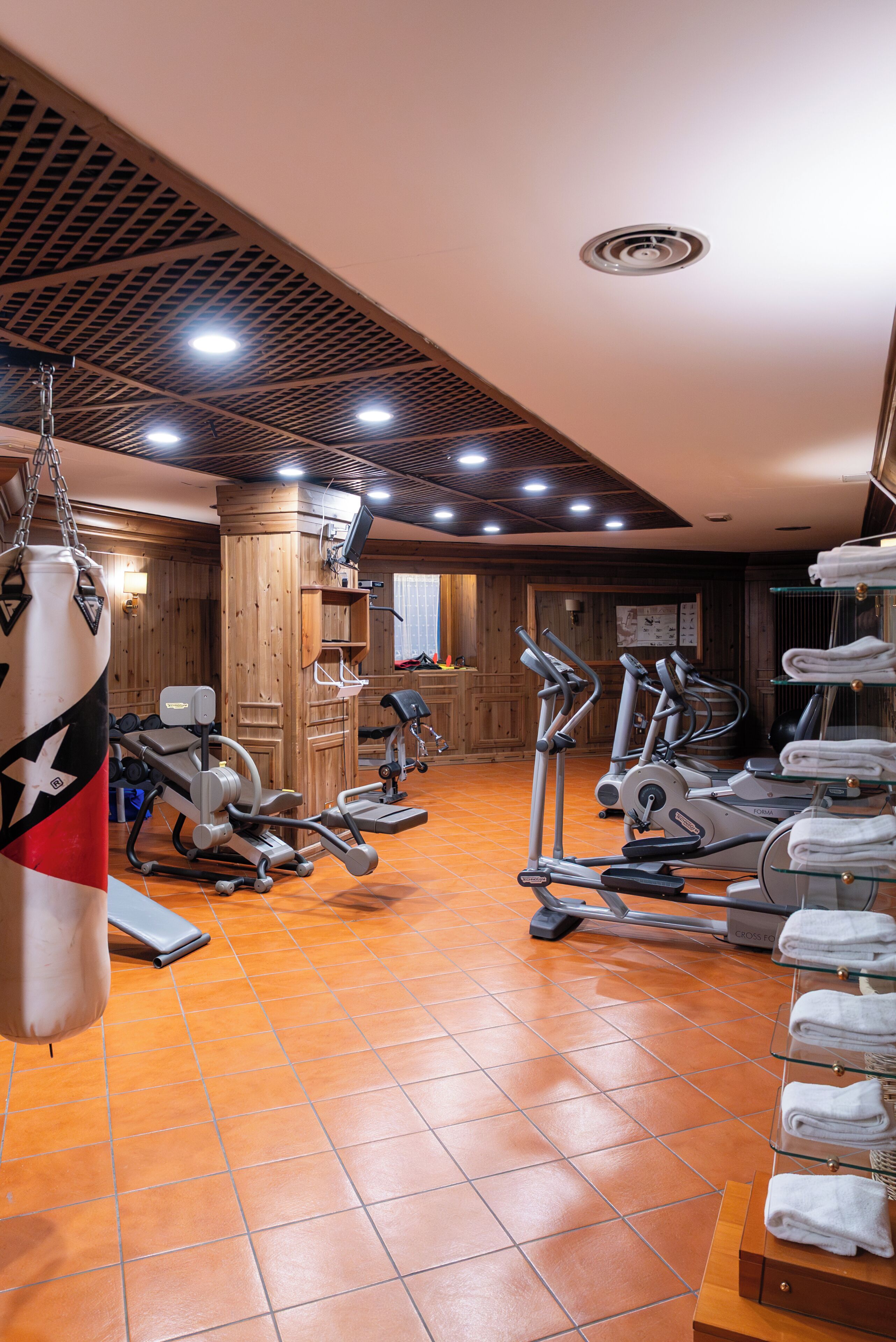 A gym with exercise equipment, a punching bag, and a wall-mounted clock.