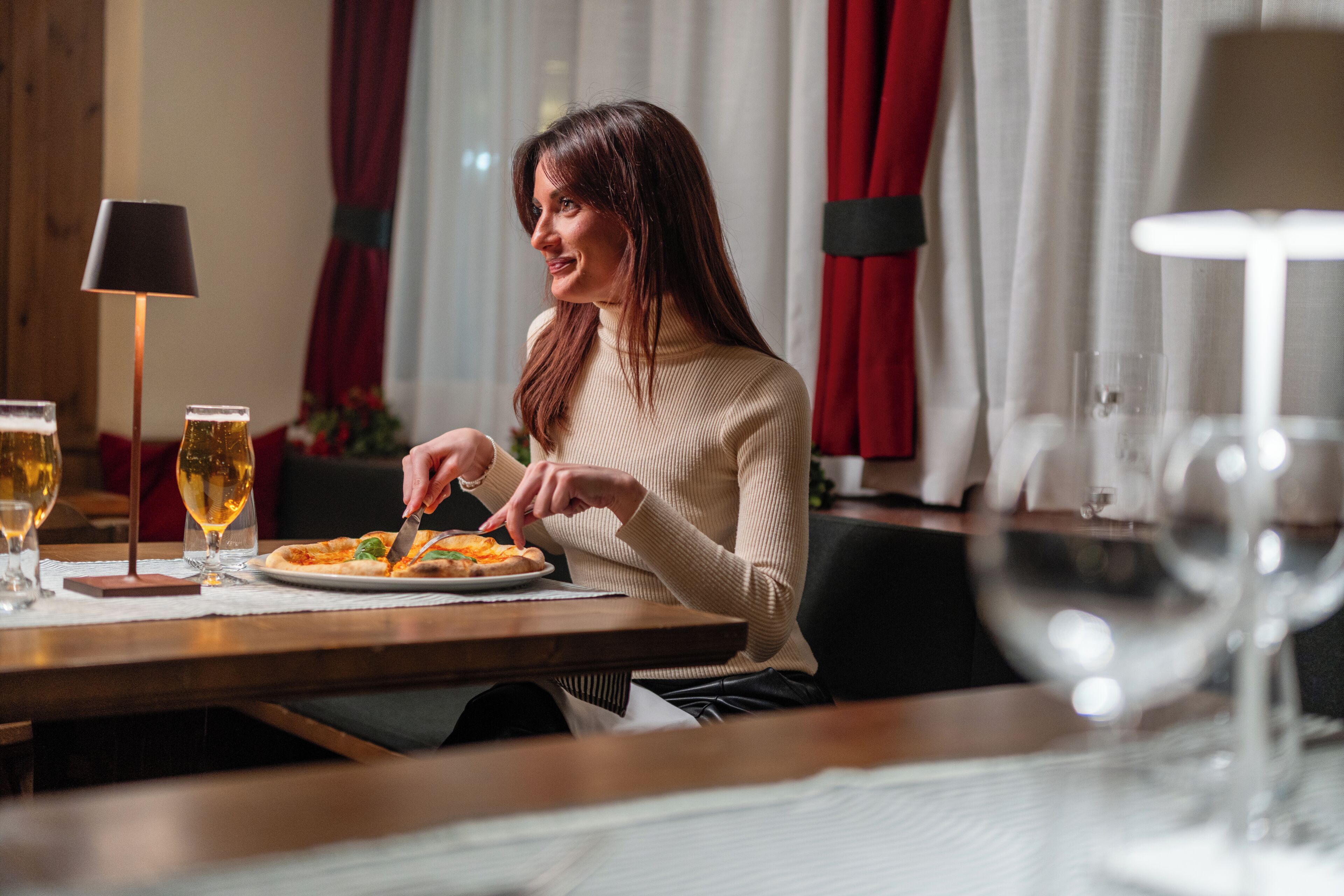 A person seated at a table with a plate of food and a glass of wine.