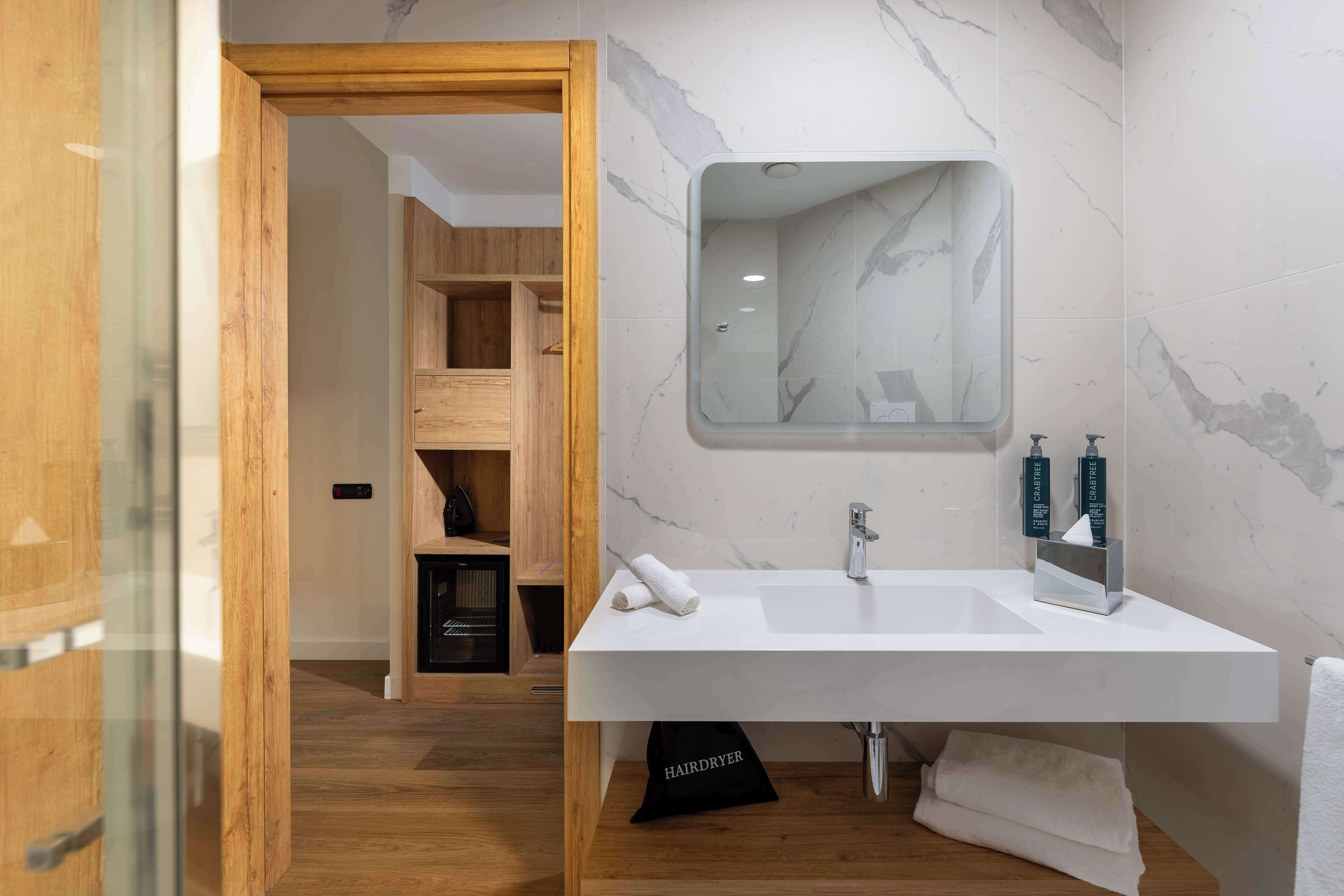 A modern bathroom with a large white sink, a mirror, and a wooden vanity.