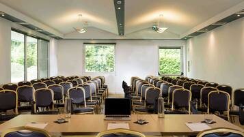 A conference room with a long table, rows of chairs, and large windows.