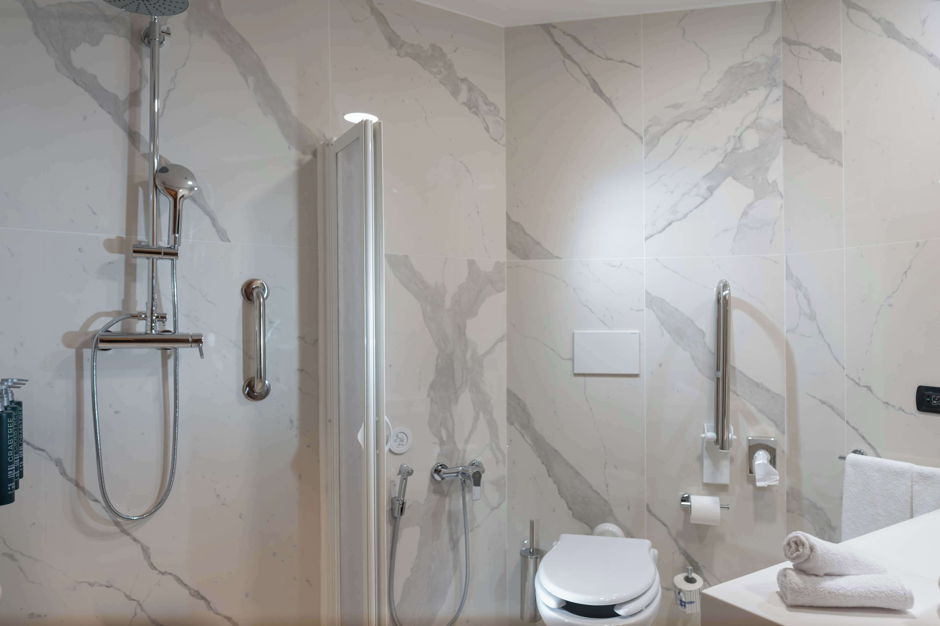 Un baño moderno con ducha de vidrio, inodoro y lavamanos con toalla.