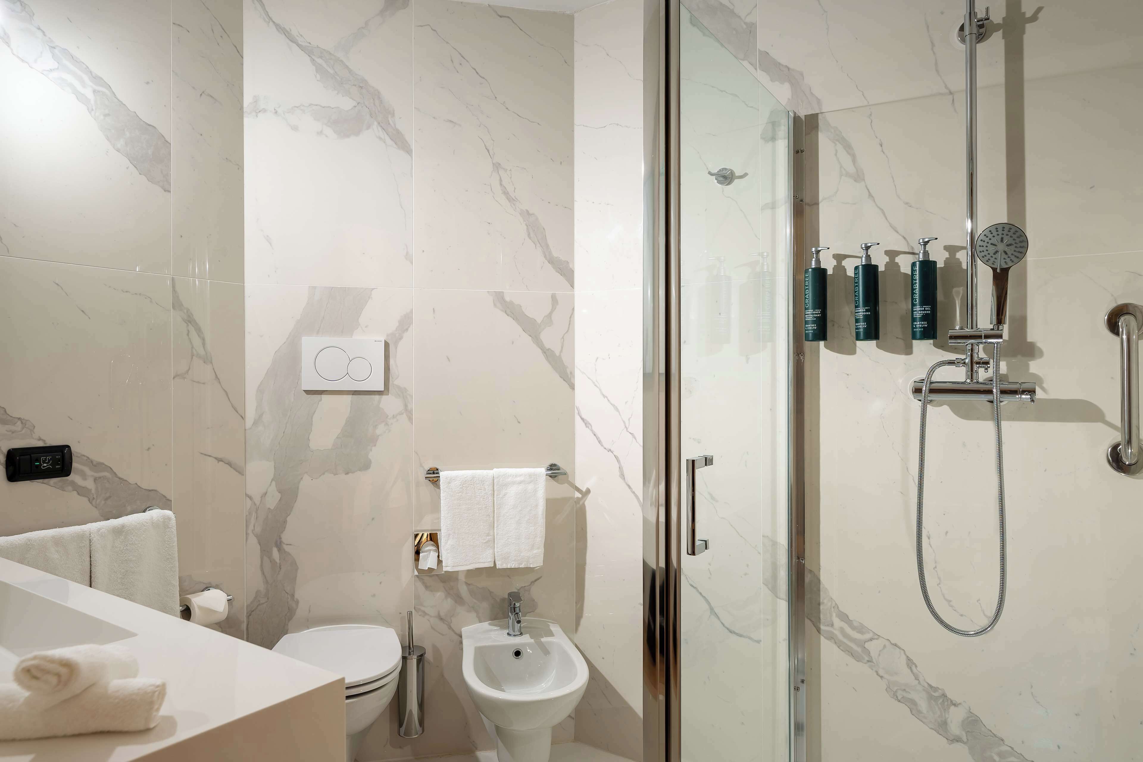Un baño moderno con ducha de vidrio, lavamanos blanco y un inodoro.