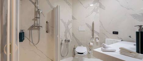 A modern bathroom with a shower, toilet, and sink, featuring marble walls and a glass-enclosed shower area.