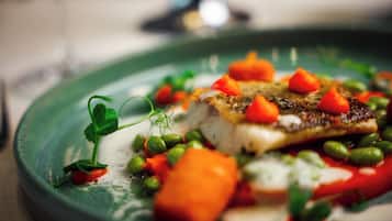 Un plato de comida con varias verduras y un trozo de pescado.