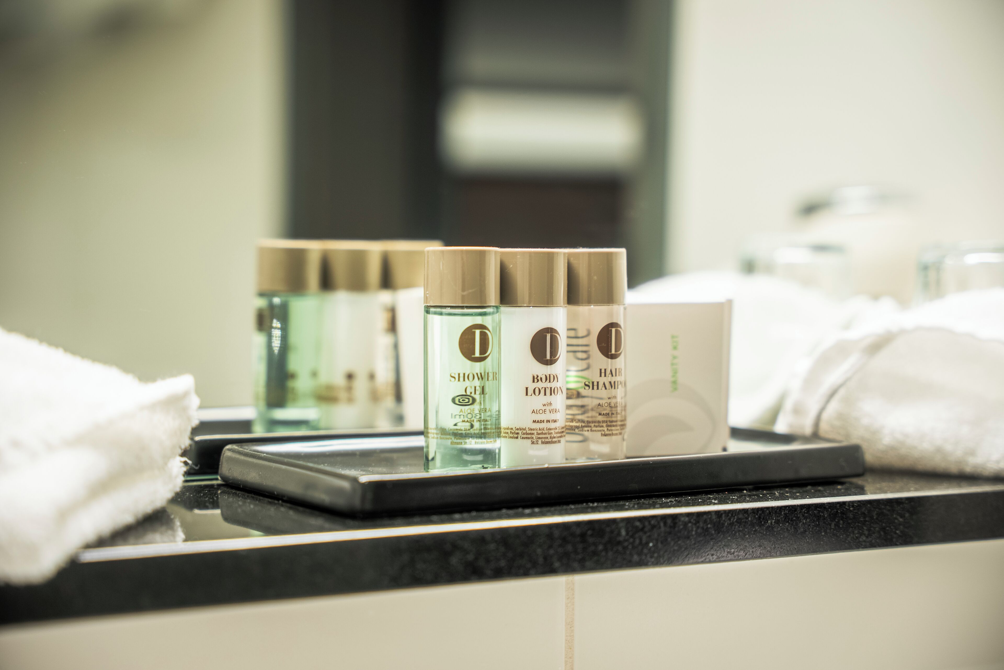 Uma bancada de banheiro com produtos de higiene pessoal, incluindo gel de banho, loção corporal e shampoo.