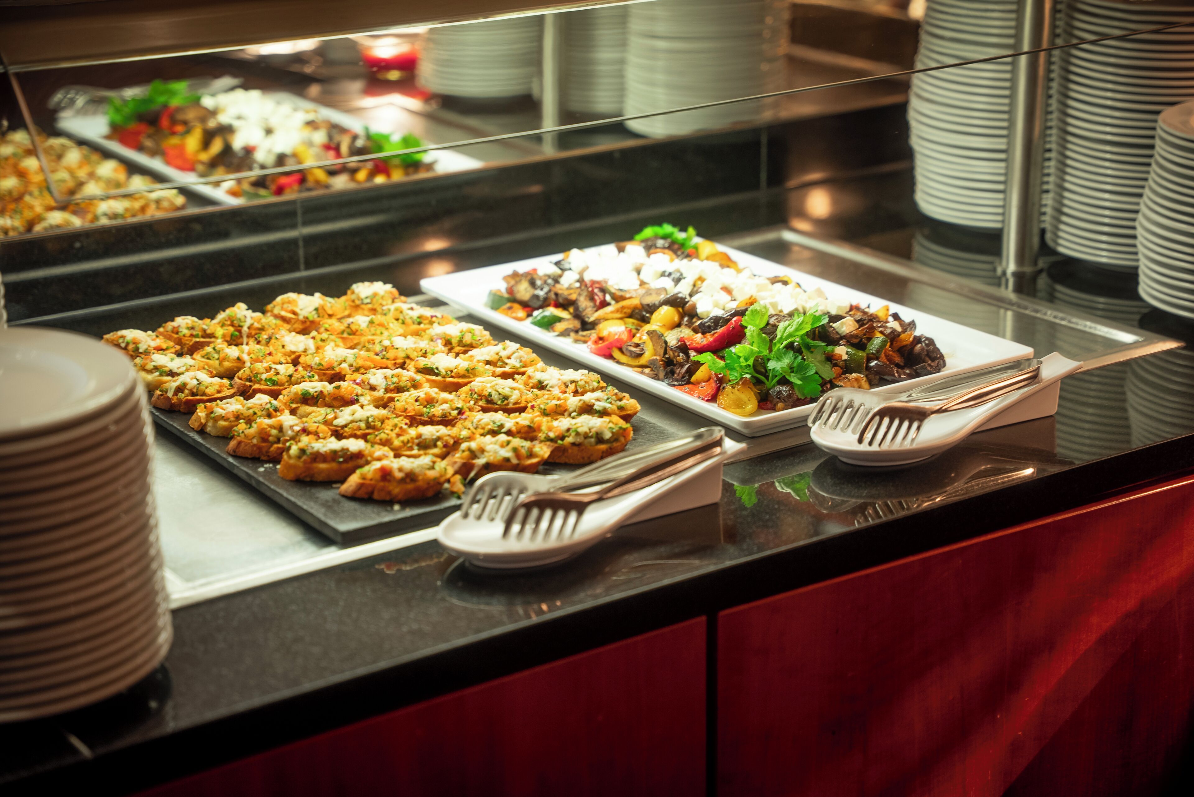 Un bufé con diversos platos, entre ellos ensaladas y aperitivos, dispuestos en bandejas.