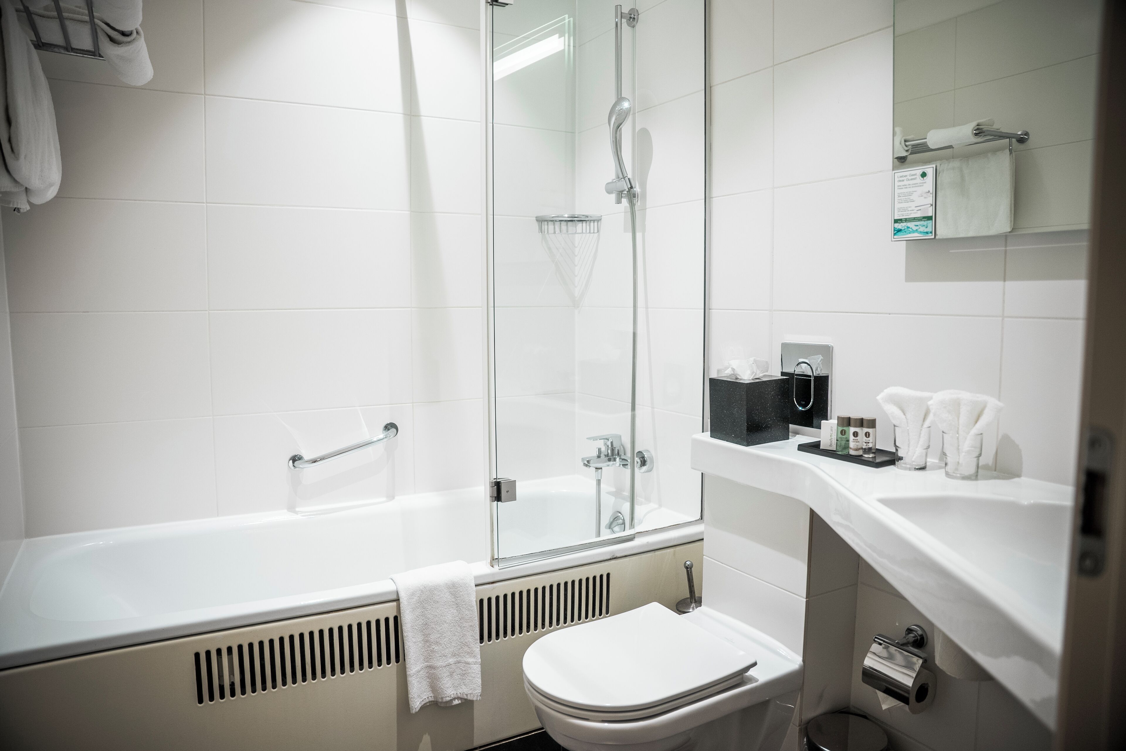 A modern bathroom with a glass-enclosed shower, a white bathtub, and a toilet.