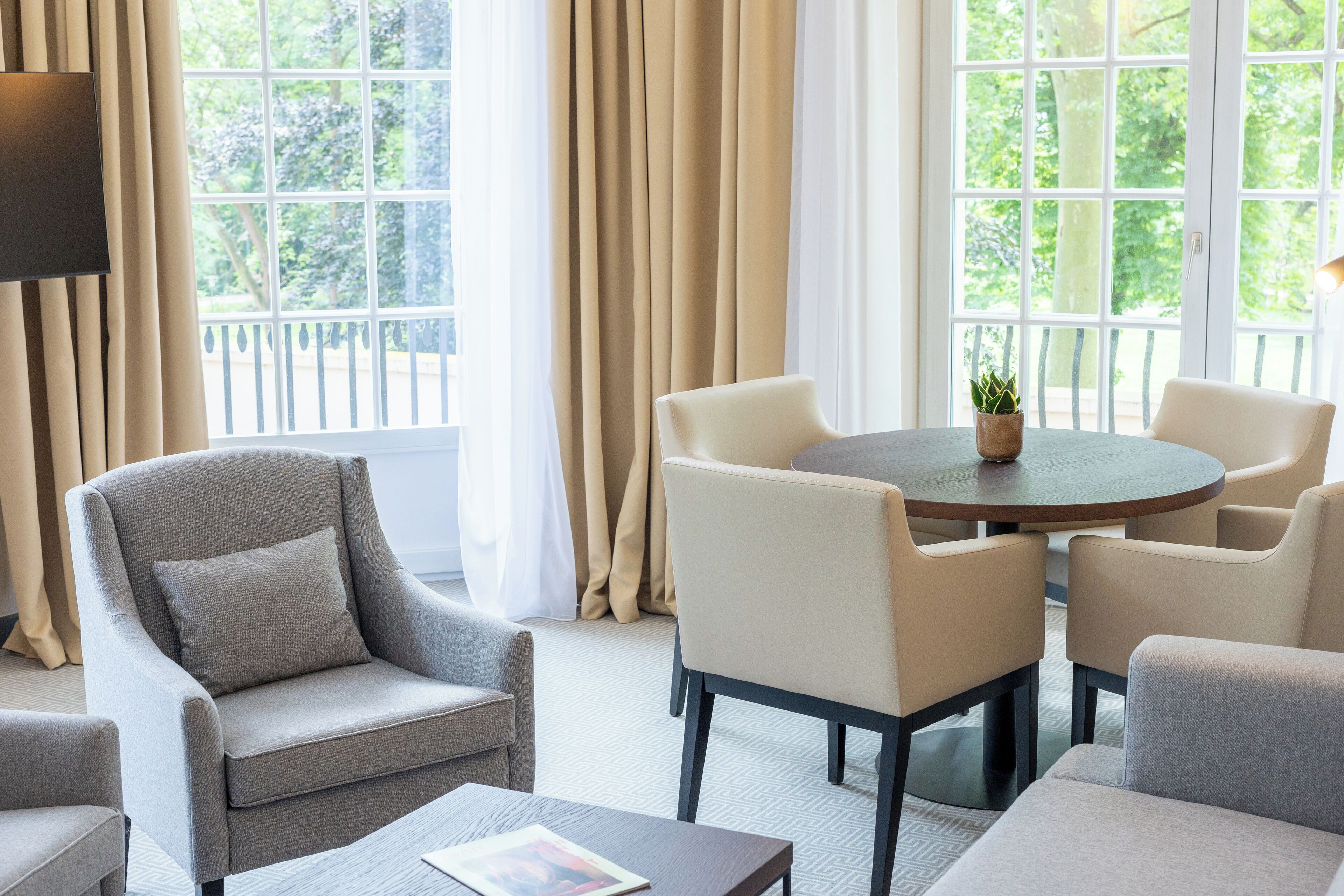 Una sala de estar moderna con una mesa redonda, sillones color beige y un sofá.
