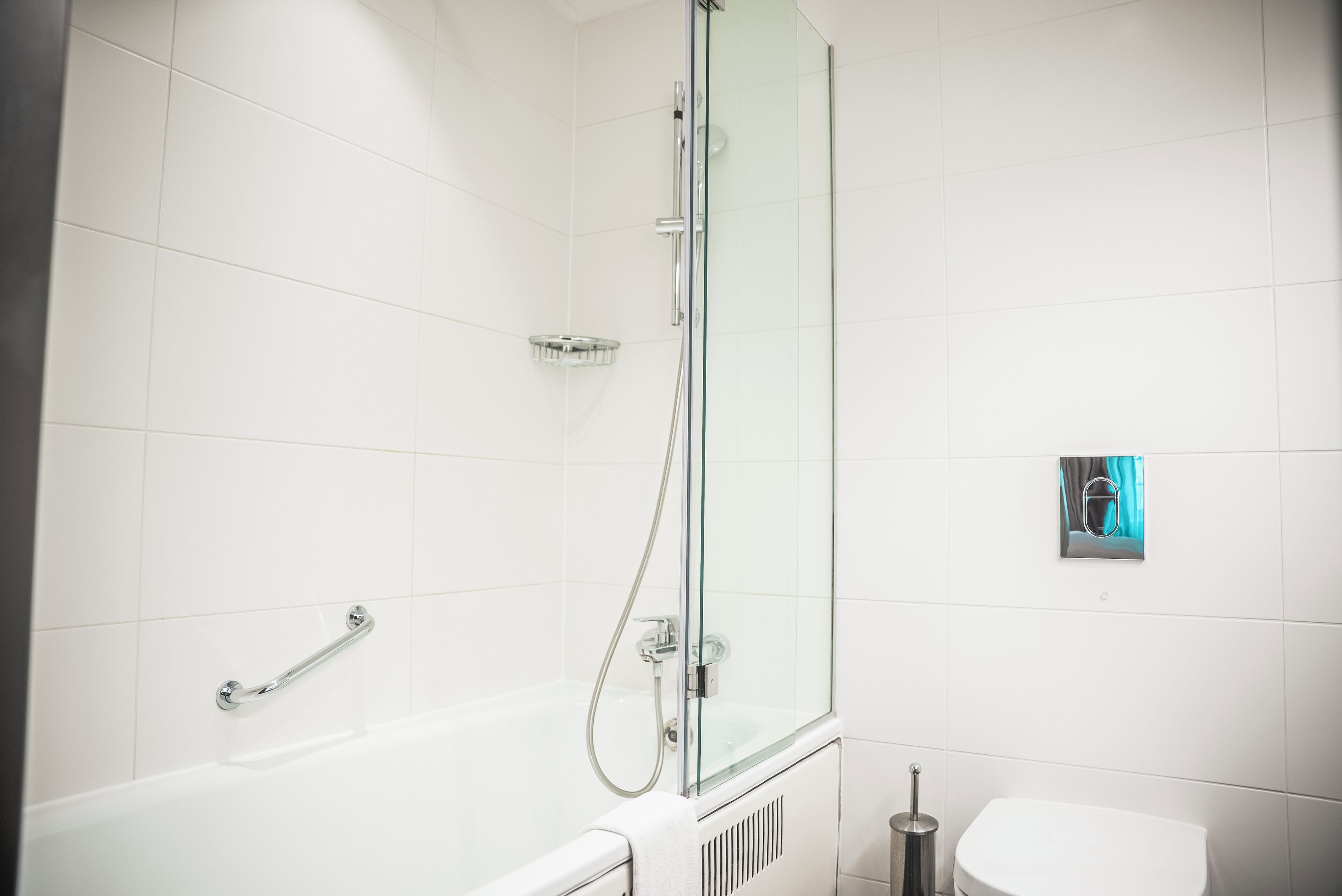 Un baño moderno con ducha de vidrio, bañera blanca y retrete.